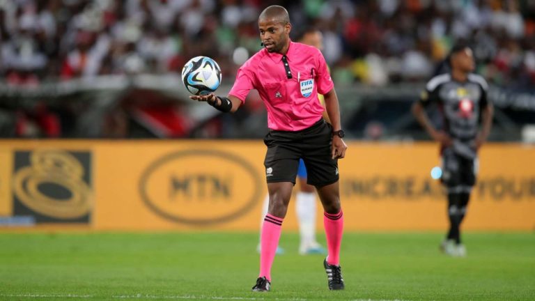 Image of a soccer referee making a contentious call, with players and coaches reacting in the background