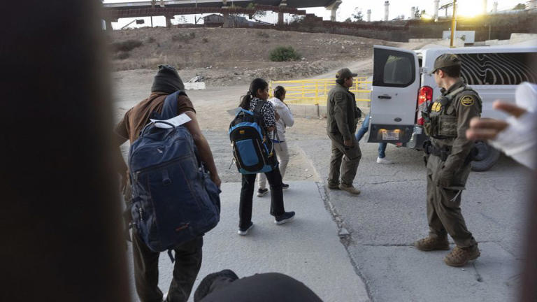 Migrants make their way to a Border Patrol van in San Diego- Imag credit: EMSN