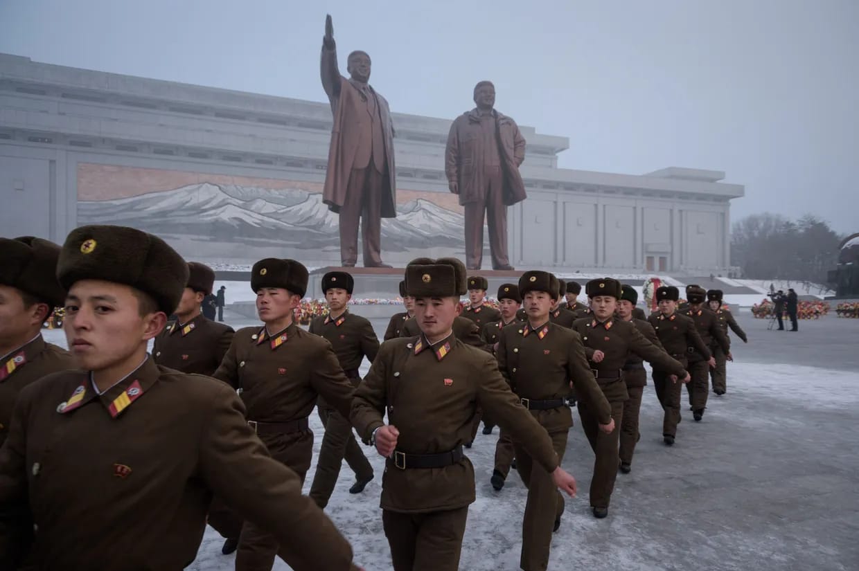Korean people's army bow to the statues of late leaders.`Image: Kyiv Independent.