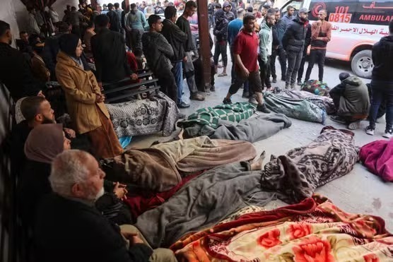 Relatives sit around the bodies of victims killed in an Israeli strike at Al-Mamdani Hospital in Gaza City on March 18, 2025. Image credit: AFP