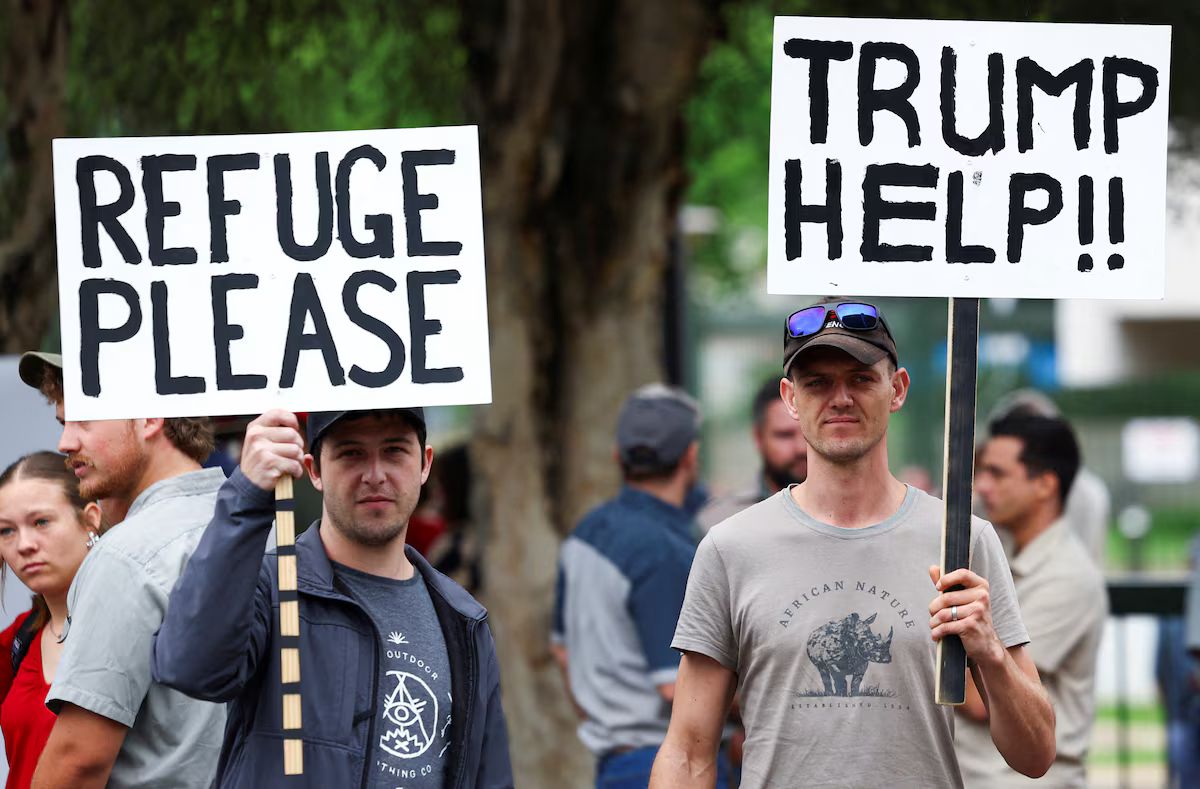 Protesters outside the U.S. Embassy in Pretoria hold placards supporting former President Donald Trump’s stance on South African land expropriation and farm attacks, calling attention to what they describe as “racist laws” and threats to white farmers. Image Source : REUTERS/Siphiwe Sibeko