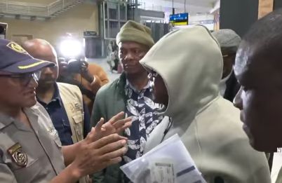 Timothy escorted to O.R. Tambo International Airport by SAPS officials.