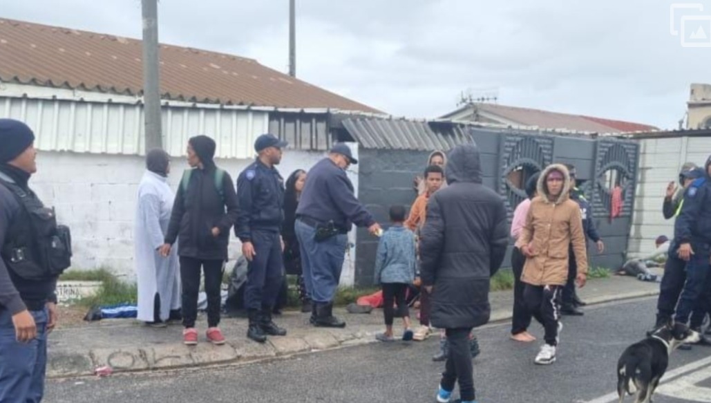 Community members and SAPS officers gather at the aftermath of the deadly shootings. Image: Cape Town, ETC.