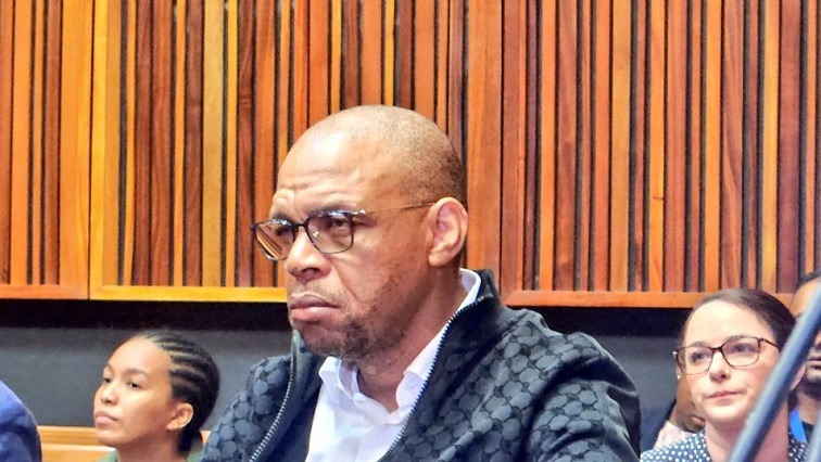 ANC's Pule Mabe Back in Court for 2017 Corruption Case 1 Image Credit:Chriselda Lewis Pule Mabe seated in a courtroom, wearing glasses and a dark jacket, with a serious expression. Several other people are visible seated behind him.