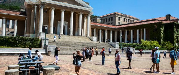 Students walk and gather outside the University of Cape Town’s iconic building under clear blue skies. Credit Image: Sunday World