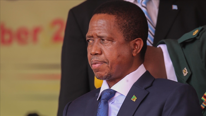 Lungu Family Appeal to SCA: Former Zambian president Edgar Lungu speaks at a podium, wearing a dark suit with a blue tie, while a uniformed guard stands in the background.