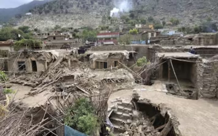 Aftershocks Rattle Afghanistan: Image shows collapsed mud-brick homes in a mountainous village, with rubble scattered across the ground and large craters exposing damaged structures beneath. Survivors and emergency responders are not immediately visible, emphasizing the desolation left by recent tremors.