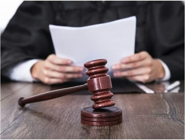 A judge in a courtroom holding legal documents, with a gavel in the foreground, symbolizing the legal debate on consent in sexual offence cases.