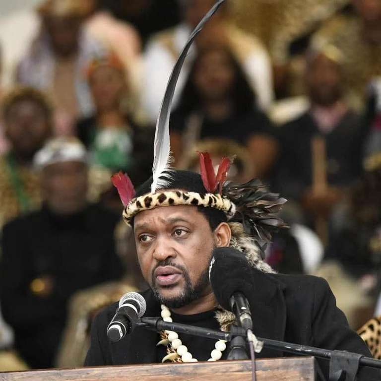 Zulu king stick fight context shows King Misuzulu addressing a crowd while wearing traditional attire with feathers and beads.