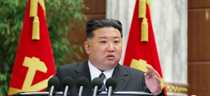 Trump and North Korea: North Korean leader Kim Jong Un speaks calmly at a podium with red flags behind him.