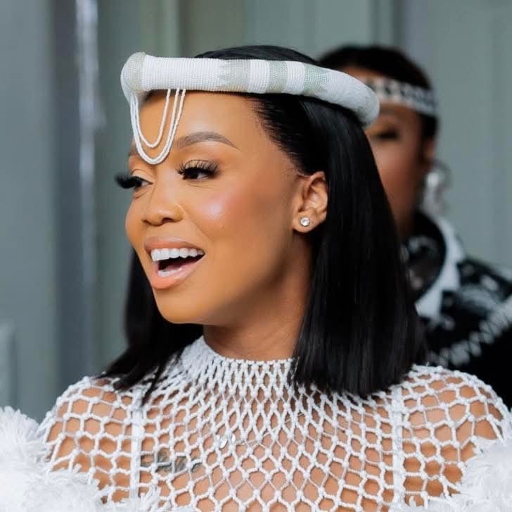 Ntando Duma Rambani smiling in traditional attire with a beaded headband and netted top, during a cultural event, amid recent copyright headlines.