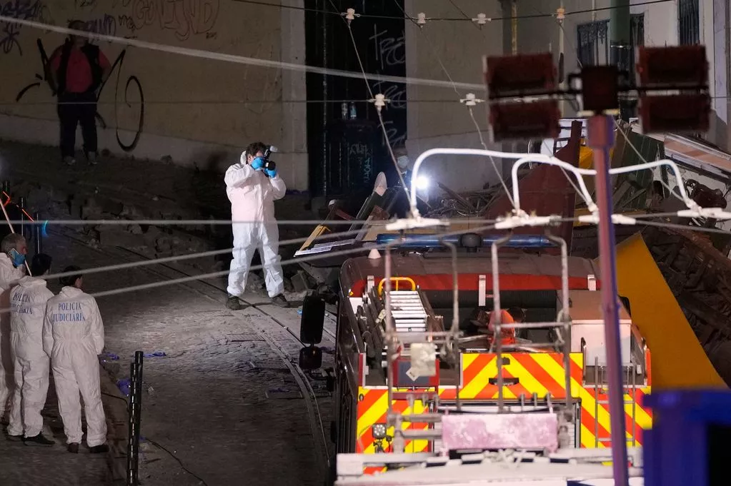Portugal funicular crash scene showing emergency responders in forensic suits investigating debris near the derailed tram at night.