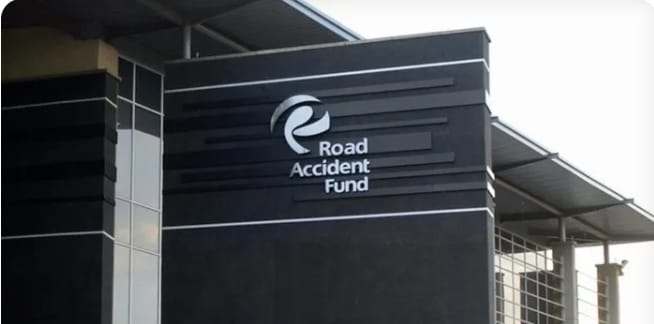 Pedestrian Gets R2.6M for Injuries – The exterior of a modern building with the logo and signage of the Road Accident Fund (RAF) displayed prominently on a dark wall under a steel roof structure.