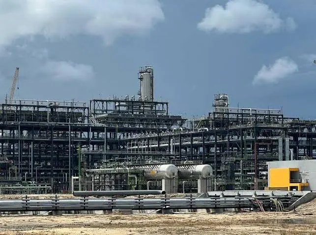 A wide view of the Dangote Refinery complex in Nigeria, showing industrial structures, pipelines, and storage units under a partly cloudy sky.