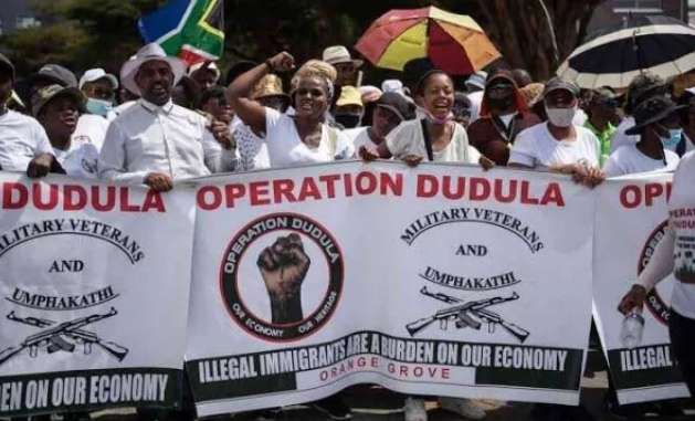 Operation Dudula March to SAHRC: A group of of operation dudula supporters march with banners displaying the group's name, slogans, and symbols, expressing views on immigration and economic concerns.