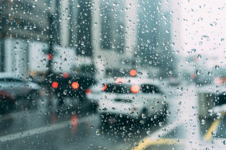 Raindrops on a car window with blurred traffic lights in the background during wet weather, illustrating the KZN heavy rainfall alert.