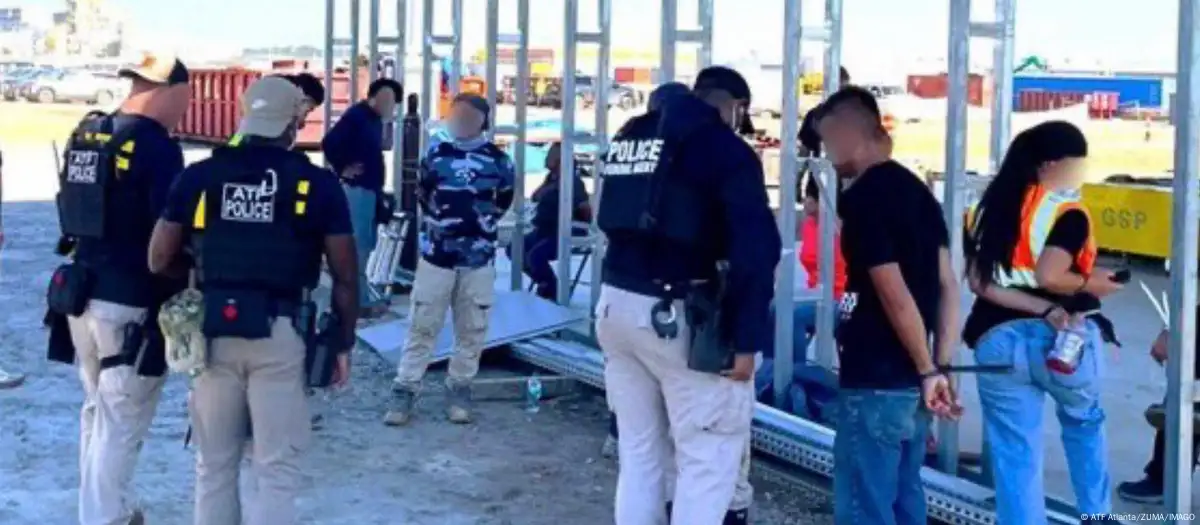 S.Korea rights probe launched after mass detention of South Korean workers in the U.S., showing U.S. immigration officers detaining multiple individuals during a raid at a Hyundai supplier factory in Georgia.