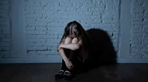 A young child sits alone in a dimly lit room, hugging their knees with their head down, reflecting the emotional impact of a child sexual assault case.
