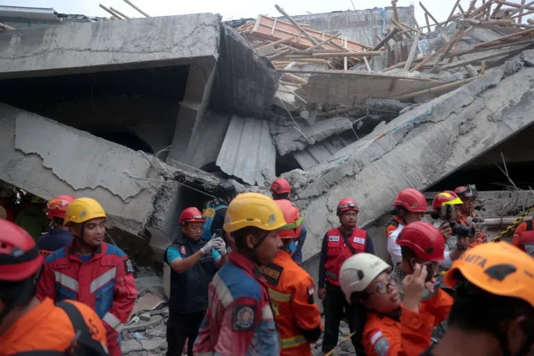 Rescue teams working at the collapsed school building in Indonesia, searching through rubble to save trapped students.