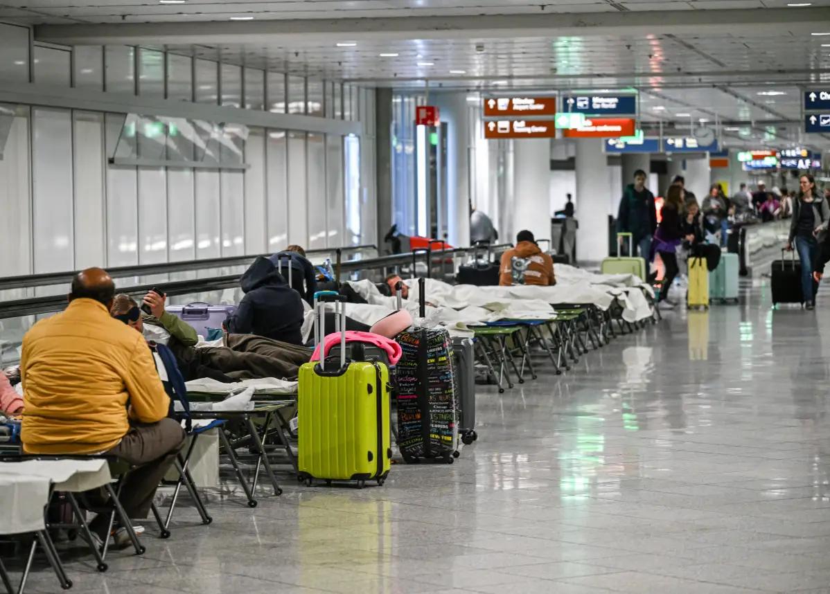 Passengers resting on cots at Munich Airport after drone sightings caused flight cancellations on October 3, 2025.